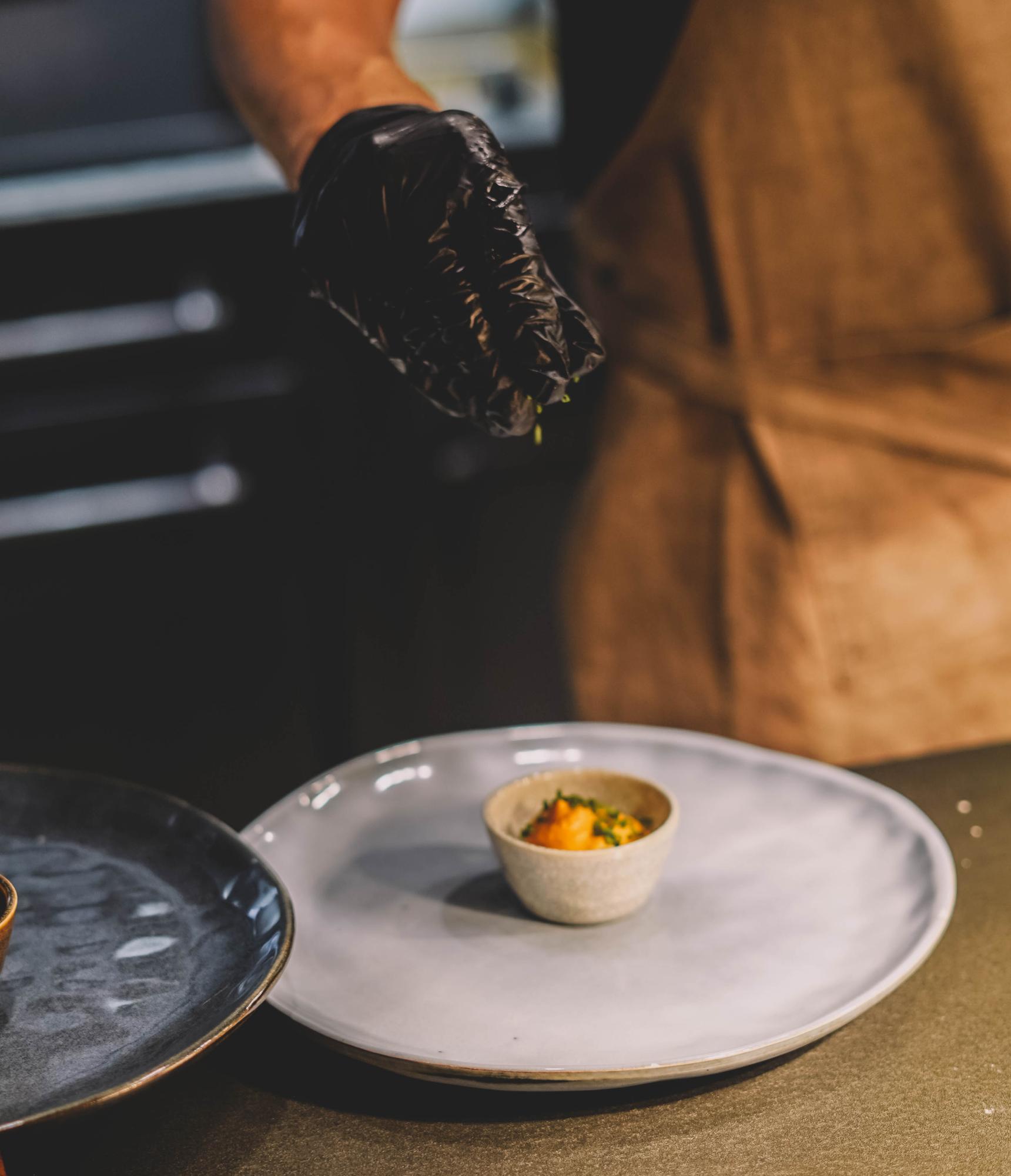chef arranging a fast plated dish in a warm studio